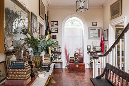 Bücherstapel auf neoklassizistischem Tisch, Holztruhe mit thailändischer Buddha-Büste in der Eingangshalle