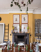 Framed hand painted warriors hang above a marble mantlepiece, decorative pineapples adorn antique urns and the table