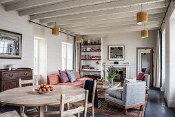 Beamed ceiling and furniture in living room of renovated 17th century stone cottage