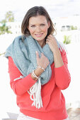 A young woman wearing a thick scarf and a coral jumper