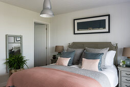 Peach quilt on double bed with gold lamp on bedside table