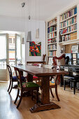 Antique chairs around wooden table in front of bookcase