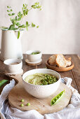 Bowl with hummus made with green pea, ingredients and bread slices