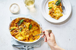 Baked squash garnished with green basil placed on white table for dinner