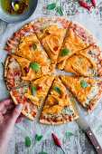 Top view of anonymous person taking slice of tasty pizza with chicken and curry placed on wooden table