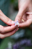 Woman threading lilac florets onto fine silver wire