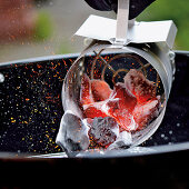 Pouring red-hot coal from a fire starter into the grill