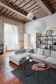 Pale sofa and tables in living room with wood-beamed ceiling