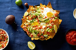 Chilaquiles mit schwarzen Bohnen, Mais, Tortillachips und Spiegeleiern