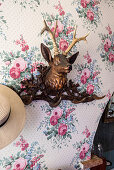 Stag's head coat rack on wall with floral wallpaper
