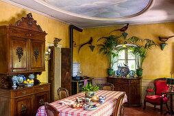 Dining table and antique sideboard in rustic kitchen-dining room with yellow walls