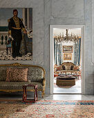 Oriental painting on marble wall above sofa next to open doorway with view of living room