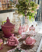 Pink crockery, sweet jars and flowers on table