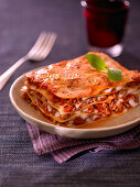 A piece of classic lasagne with a basil leaf