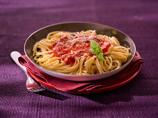 Spaghetti with tomato sauce and a basil leaf
