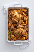 Lemon chicken with bacon, potatoes and thyme in a baking dish