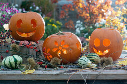Halloween pumpkins with faces and floral decorations, decorative pumpkins, chestnuts and branch with rose hips