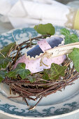 Selbstgemachter Babyschuh aus Papier im Nest als Tischkärtchen