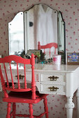 Red chair with turned spindles at old dressing table with triple mirror