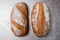 Two freshly baked loaves of brown bread