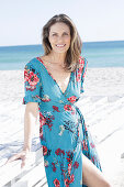 A long-haired woman on the beach wearing a summer dress