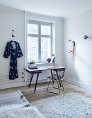 Classic chair and desk below window next to kimono hung on wall