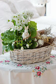 Basket with primrose, horned violets, and branches as an Easter decoration with an Easter bunny and Easter eggs