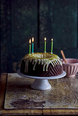 Chocolate Bundt cake with a pistachio glaze and four burning candles