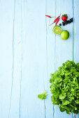 Green lettuce and fruits on a light blue wooden surface
