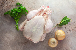 Ingredients for chicken broth: a whole raw chicken, herbs and onions