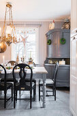 Rustic, set dining table and grey sideboard in kitchen-dining room decorated for Christmas