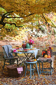 A table laid under a tree in an autumnal garden