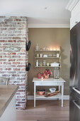 White table with houseplant and lantern below shelves in kitchen