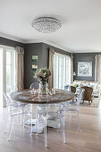 Round, solid-wood table and transparent chairs in open-plan interior