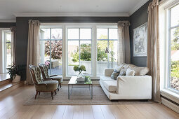 Upholstered armchairs, coffee table and light sofa in front of window in open living room