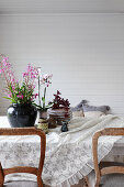 Dining table with rustic chairs in room with white lacquered wood panelling