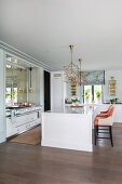 White island counter and designer chairs in elegant, open-plan kitchen