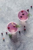 Two glasses of a cranberry and rosemary drink