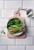 Green mini asparagus and fresh spinach in a ceramic bowl