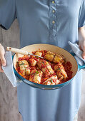 Woman holding a baking dish with Greek cabbage rolls