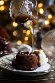 A holiday table set up with sticky toffee pudding with pecan caramel sauce being drizzled on top