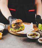 Hand holding burger with fried onions, cheese and lettuce leaf