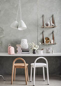 Two stools at the desk, above them pendant lamp and wall shelves with suede straps