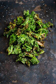 Kale chips with coarse salt on a baking sheet