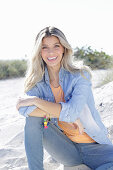 A young blonde woman wearing denim and an apricot top