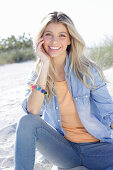 A young blonde woman wearing denim and an apricot top