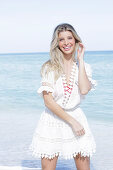 A young blonde woman wearing a white embroidered summer dress