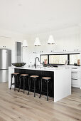 Bar stools at island counter in modern monochrome kitchen