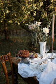 Bundt cake and flowers on festive table in garden