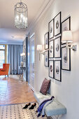 Gallery of pictures above upholstered bench in hallway of elegant apartment